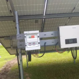 Panel słoneczny z zamontowaną skrzynką rozdzielczą i falownikiem SOFAR, instalacja na trawniku.