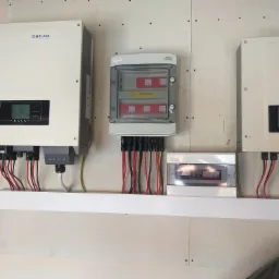 Dwa białe inwertery SOFAR zamontowane na ścianie, połączone kablami z rozdzielnicą i zabezpieczeniami w szarej obudowie KENO, widoczne również kable ochronne i przewody w kolorach czerwonym i czarnym.