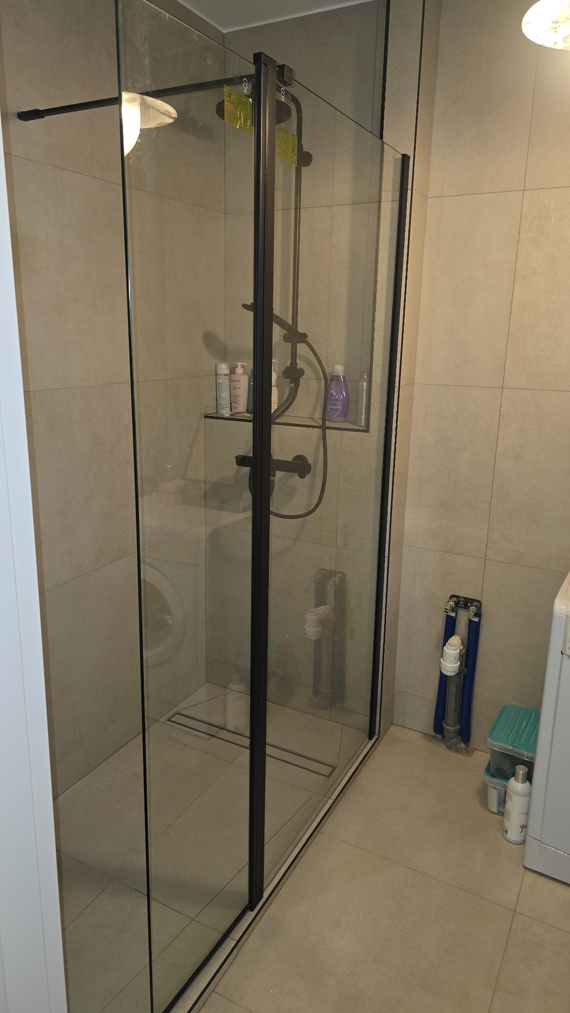 Nowoczesna kabina prysznicowa z czarnymi profilami w łazience w Gdańsku. Widoczna armatura i płytki w neutralnych odcieniach. Minimalistyczny design.