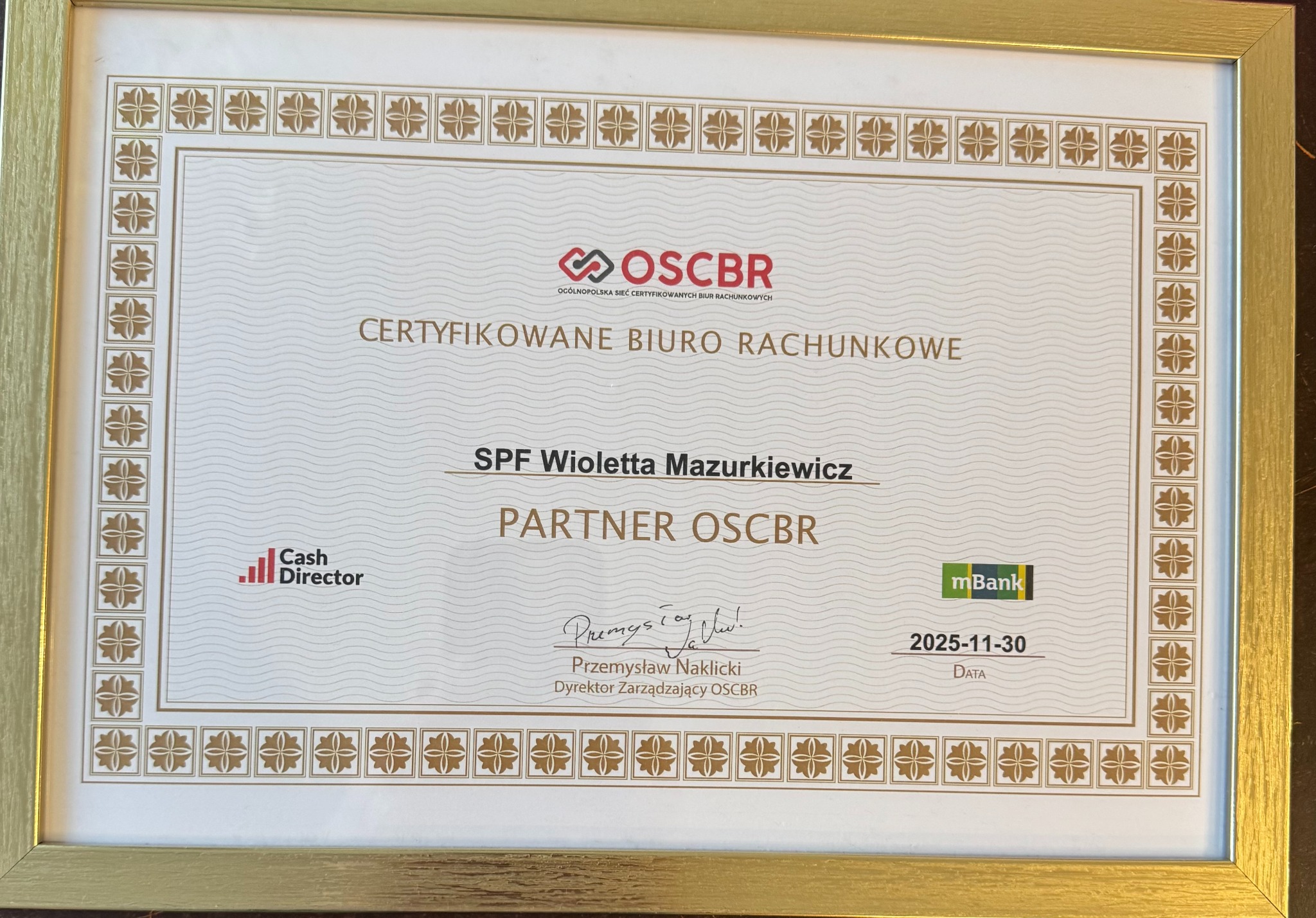 Certyfikat 'Certyfikowane Biuro Rachunkowe' SPF Wioletta Mazurkiewicz, Partner OSCBR, w złotej ramce. Data ważności: 2025-11-30. Logo OSCBR, Cash Director i mBank.