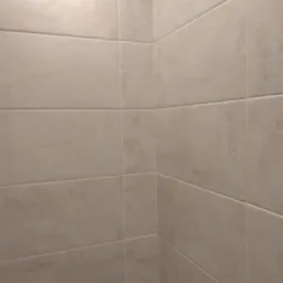 Beżowe, matowe płytki ceramiczne na ścianach w rogu łazienki, widoczny fragment armatury.