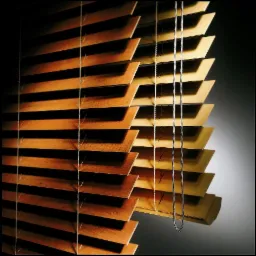 Częściowo otwarte drewniane lamele z widocznym sznurkiem i łańcuszkiem sterującym, oświetlone z boku, tworzące grę światła i cienia.