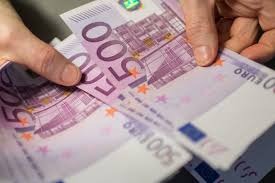 Dłonie trzymające plik banknotów 500 euro, z widocznymi znakami wodnymi i elementami zabezpieczeń.