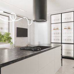 JESKA.DESIGN Magdalena Jerzewska - Wizualizacja nowoczesnej kuchni z wyspą, czarnym okapem cylindrycznym i przeszklonymi szafkami z podświetleniem, na blacie wazon z zielonymi gałązkami.