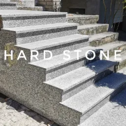 Zewnętrzne schody z szarego, ziarnistego granitu, prowadzące do budynku z ceglanym wykończeniem, częściowo zarośnięte mchem.