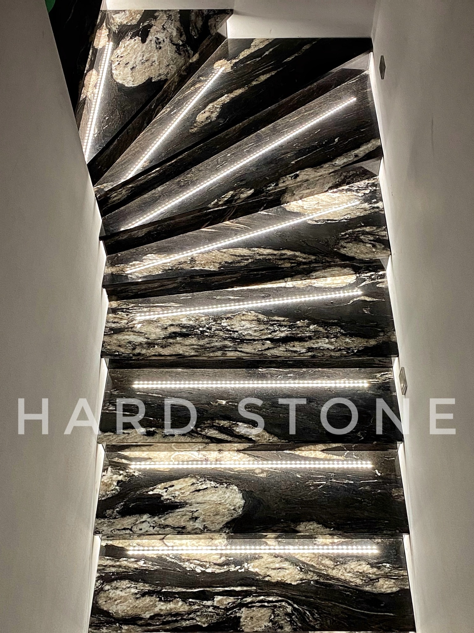 Kamienne schody w Strzegomiu z podświetleniem LED, wykonane z czarnego kamienia z białymi żyłami, widok z dołu.