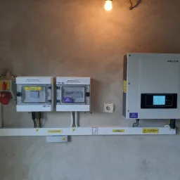 Rozdzielnice PV DC i AC, falownik Sofar Solar zamontowane na ścianie z widocznymi przewodami i oznaczeniami ostrzegawczymi, oświetlone żarówką