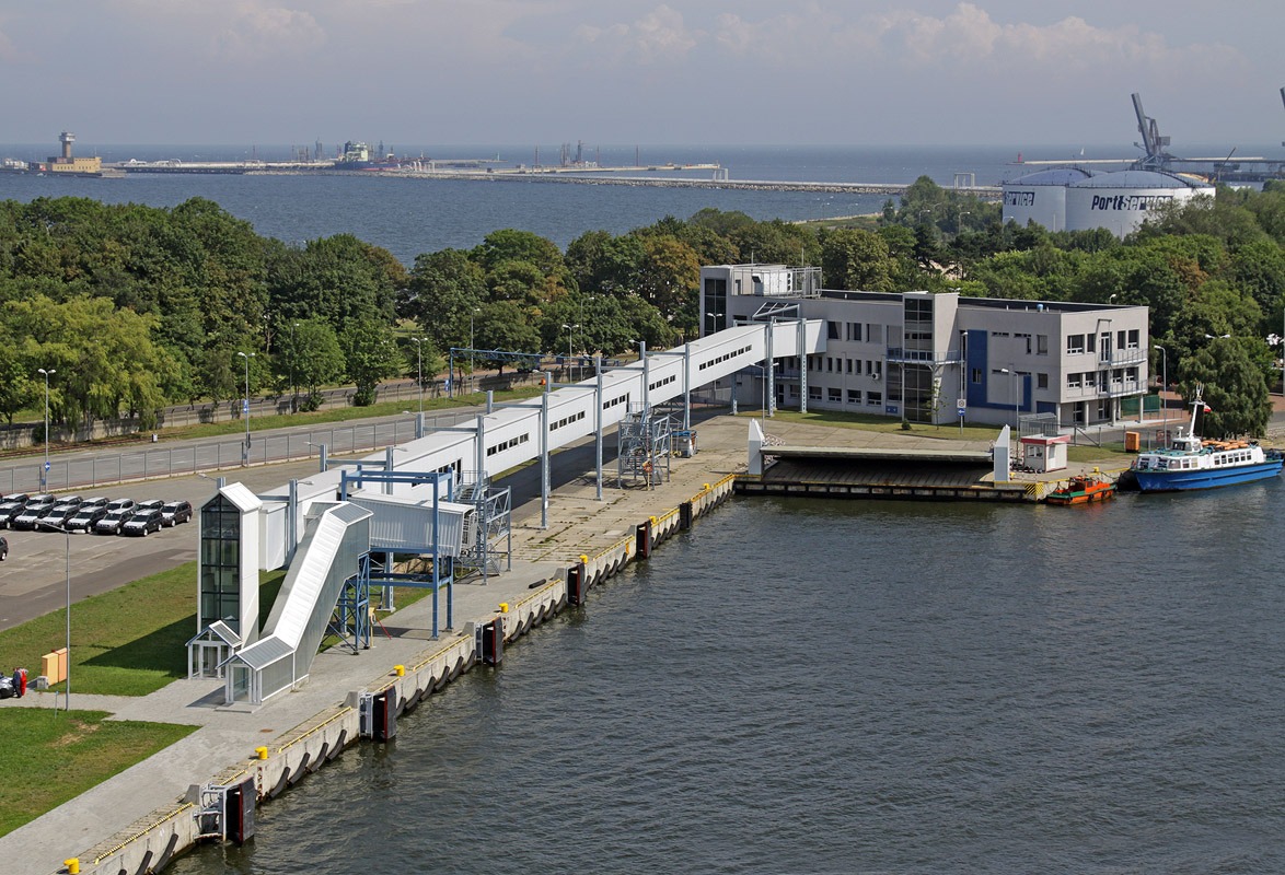 Terminal promowy Gdańsk Westerplatte widziany z góry, z widocznymi elementami centrali wentylacyjno-klimatyzacyjnej, budynkiem obsługi, nabrzeżem z łodziami i oddalonymi elementami portu.