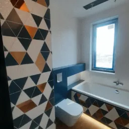 Wykończona łazienka w Turzy Śląskiej z geometrycznymi płytkami w odcieniach bieli, granatu i miedzi na ścianie i obudowie wanny, z podświetleniem pod wanną i wiszącą toaletą.
