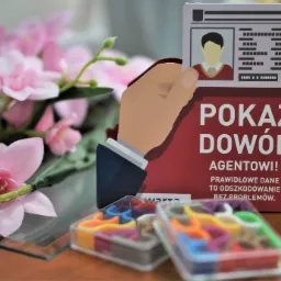 Stylizowana grafika z ręką trzymającą dowód tożsamości, hasło 'Pokaż dowód agentowi! Prawidłowe dane to odszkodowanie bez problemów' oraz dekoracyjne kwiaty i pojemniki z kolorowymi gumkami...