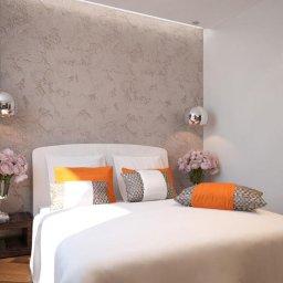Da Vinci Arte Sp. z o.o. - Elegancka sypialnia z łóżkiem z białymi prześcieradłami, pomarańczowymi i wzorzystymi poduszkami, dekoracyjną ścianą w odcieniach szarości, srebrnymi lampkami nocnymi i bukietami różowych kwiatów...