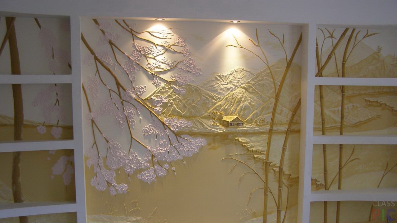 Relief na ścianie przedstawiający pejzaż górski z kwitnącymi drzewami i domkiem nad jeziorem, oświetlony dwoma punktowymi lampami, z półkami po bokach.