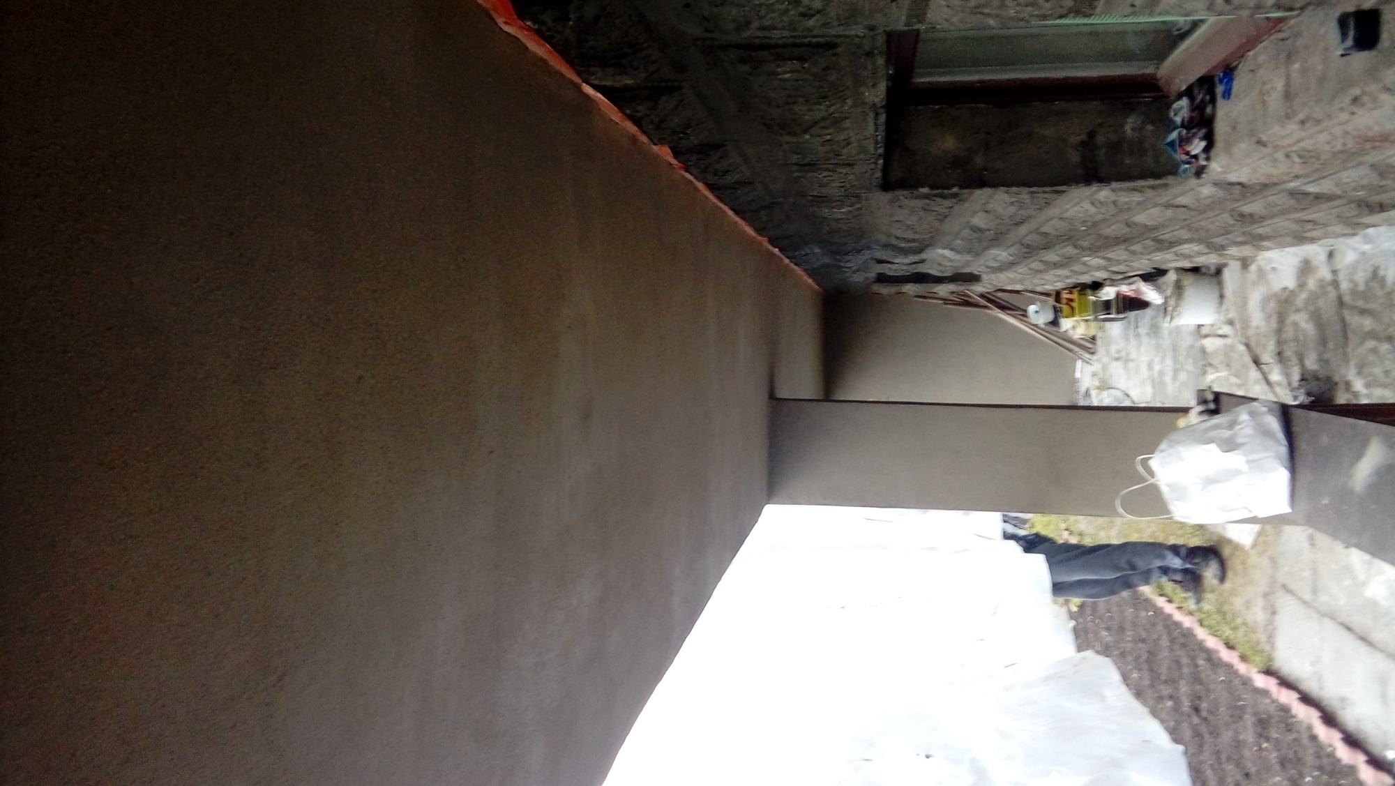 Świeżo otynkowana ściana zewnętrzna budynku w Bielsko-Białej, widoczne ślady prac murarskich i przygotowania do dalszych etapów wykończeniowych, zarys kostki brukowej na podłożu.