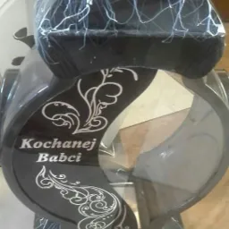 Czarny lampion nagrobny z białymi zdobieniami i napisem 'Kochanej Babci'.