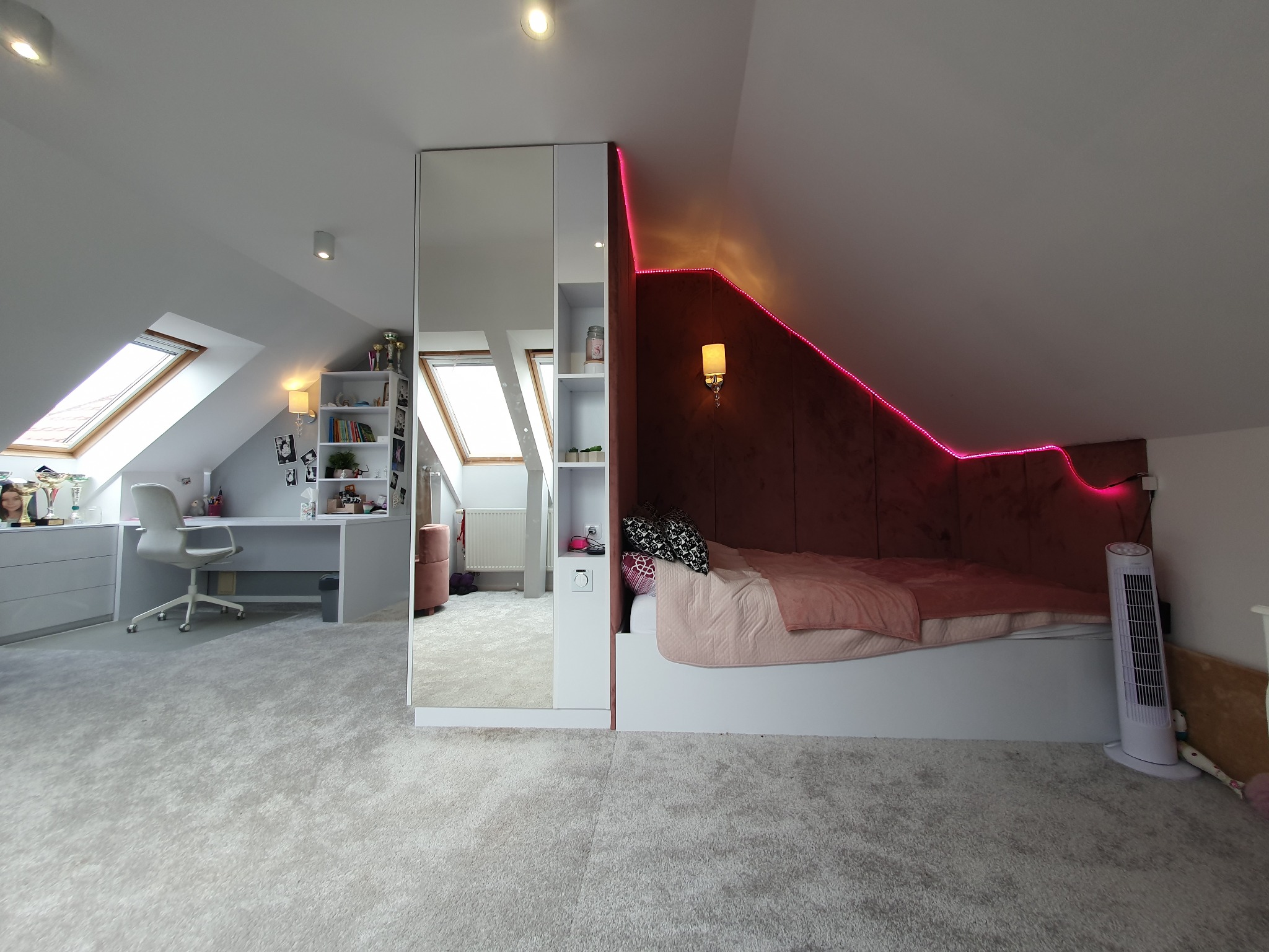 Pokój na poddaszu z łóżkiem w zabudowie, oświetleniem LED, biurkiem przy oknie dachowym i szafą z lustrem.