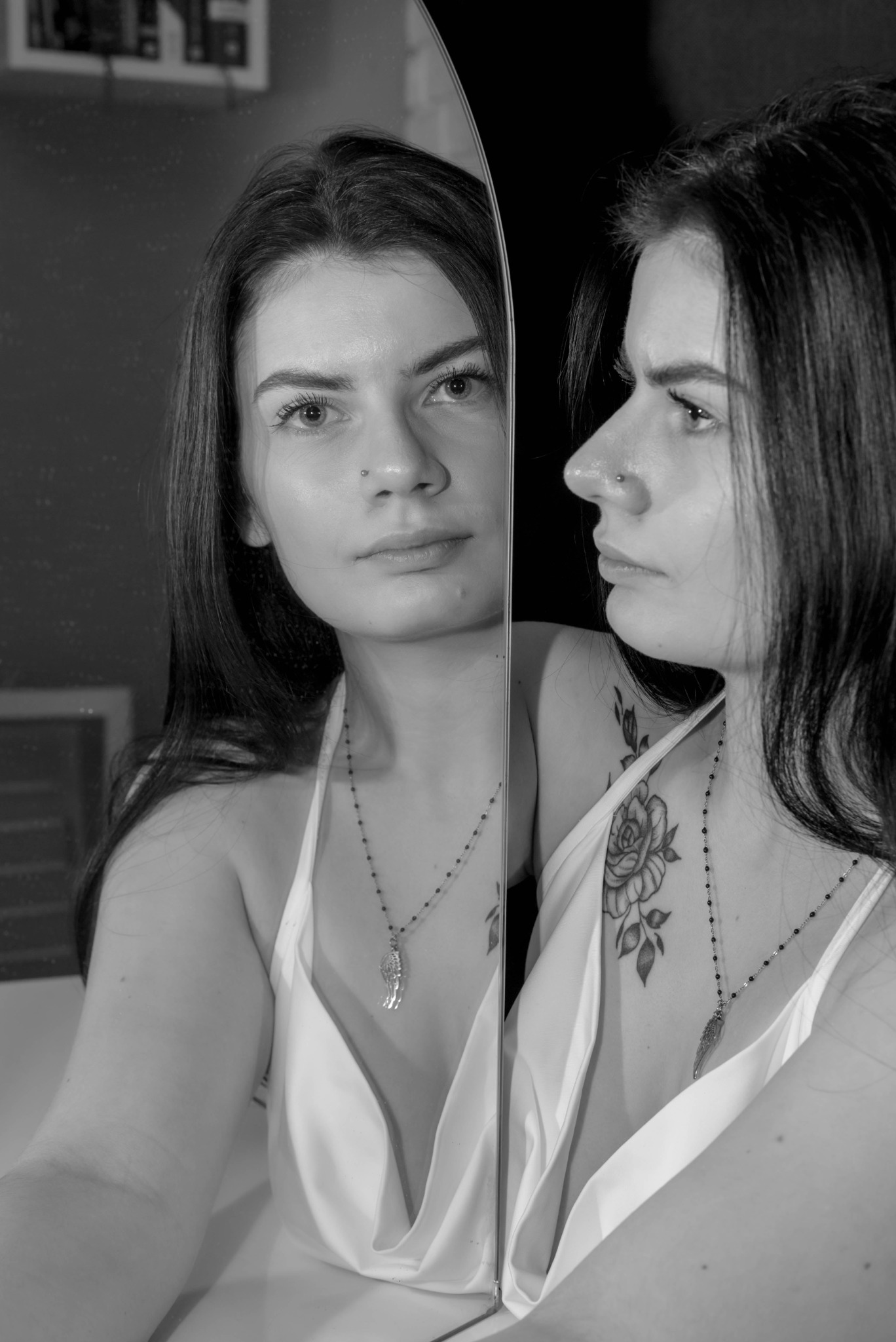 Portret kobiety w bieliźnie, z tatuażem róży na ramieniu, pozującej przed lustrem, czarno-białe zdjęcie.