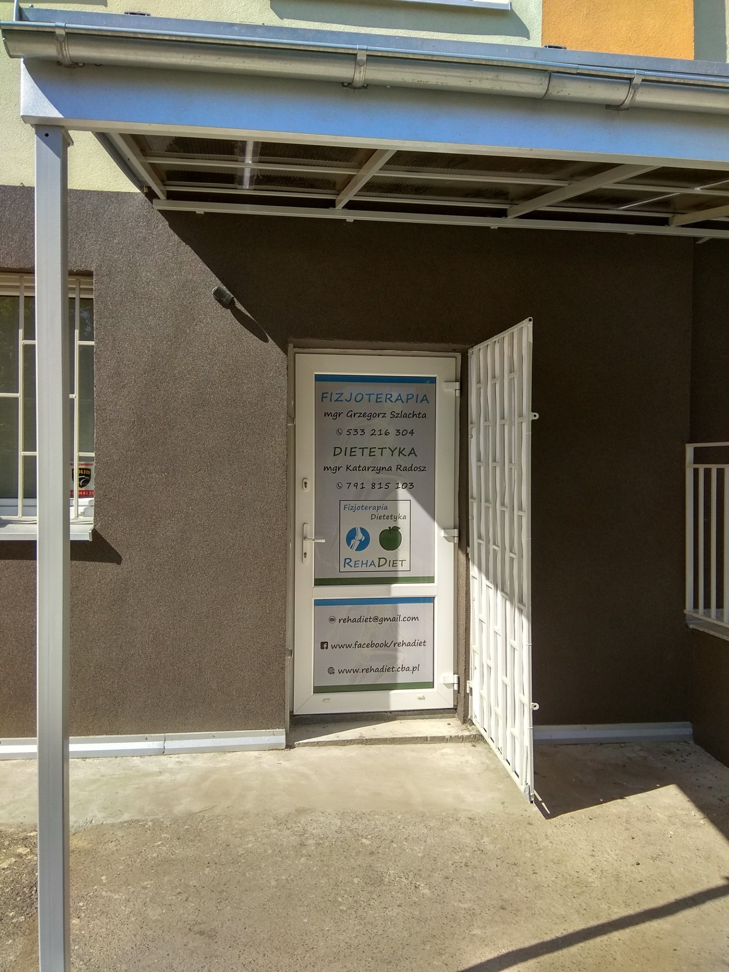Wejście do gabinetu z informacją o fizjoterapii i dietetyce, widoczne dane kontaktowe i logo RehaDiet.