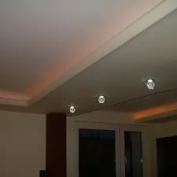 Wykończony sufit podwieszany z oświetleniem LED w kolorze ciepłej bieli i trzema okrągłymi lampami punktowymi z metalowymi obudowami.