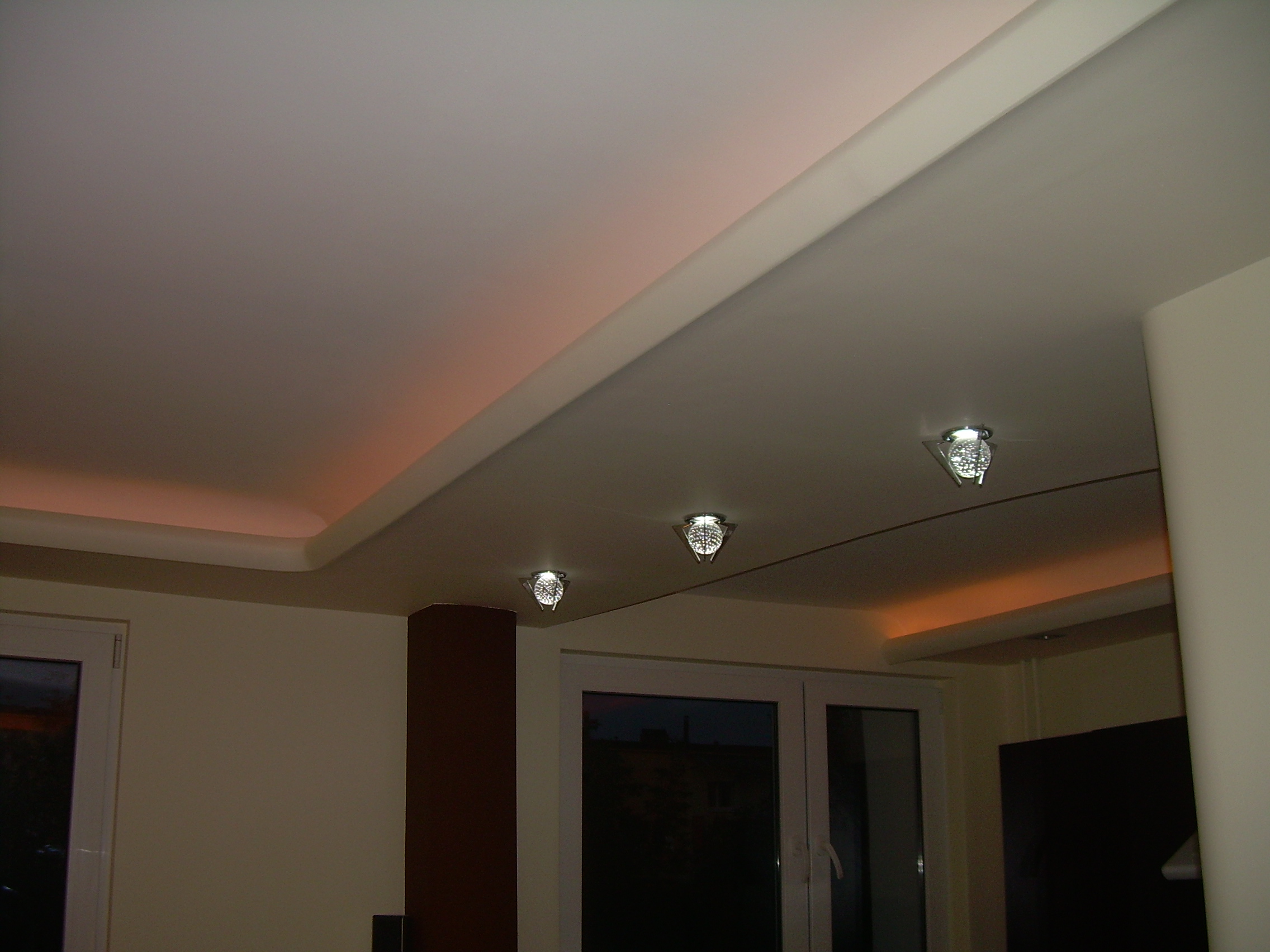 Wykończony sufit podwieszany z oświetleniem LED w kolorze ciepłej bieli i trzema okrągłymi lampami punktowymi z metalowymi obudowami.