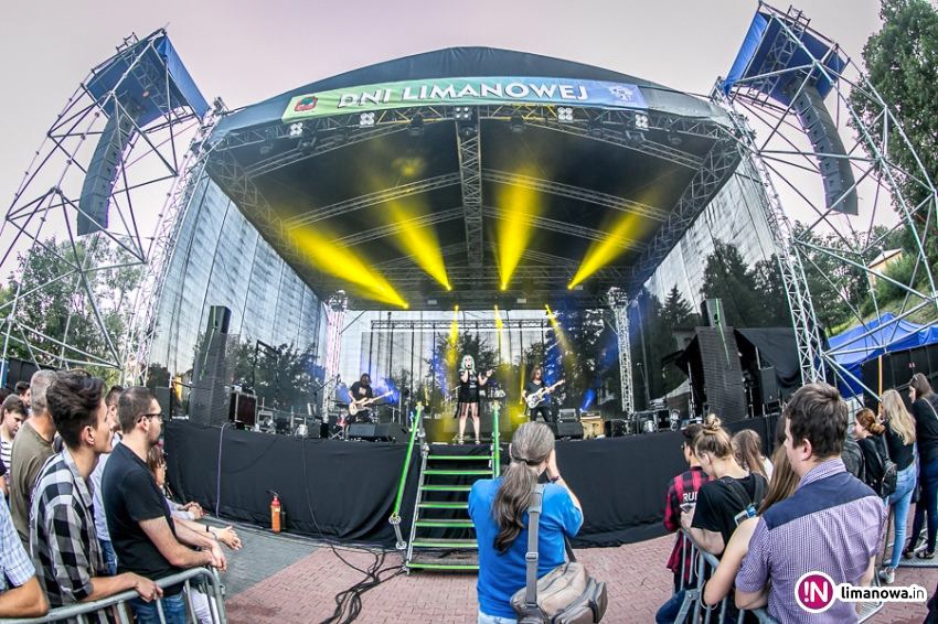 Scena plenerowa podczas koncertu Dni Limanowej, oświetlona reflektorami, z zespołem muzycznym na podeście i publicznością za barierkami.