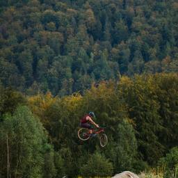 PN Patryk Nawrocki - Rowerzysta w kasku wykonuje skok na rowerze górskim z rampy, w tle las w okolicach Warszawy.