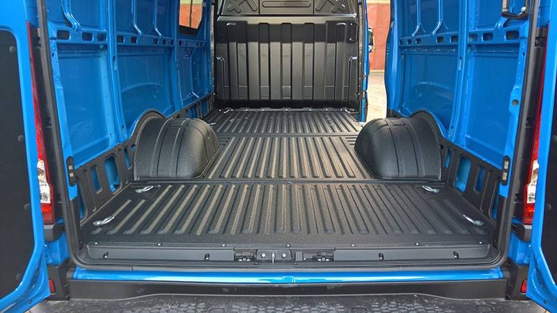 Wnętrze niebieskiego furgonetki z otwartymi drzwiami, widoczna paka z czarną, ryflowaną podłogą i nadkolami, zabezpieczona przed korozją.