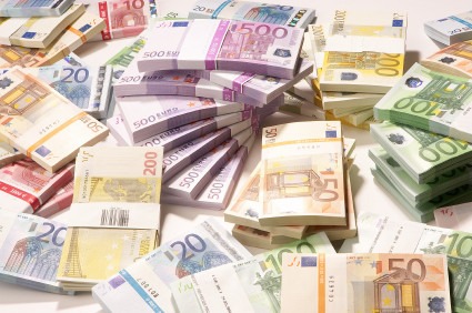 Stosy i pojedyncze banknoty euro o różnych nominałach (10, 20, 50, 100, 150, 200, 500) ułożone na białym tle, z banderolami na spiętych paczkach.