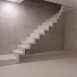 Minimalistyczne, białe schody wspornikowe na tle ściany o fakturze betonu, oświetlone od góry, widoczne gniazdka elektryczne na ścianie.