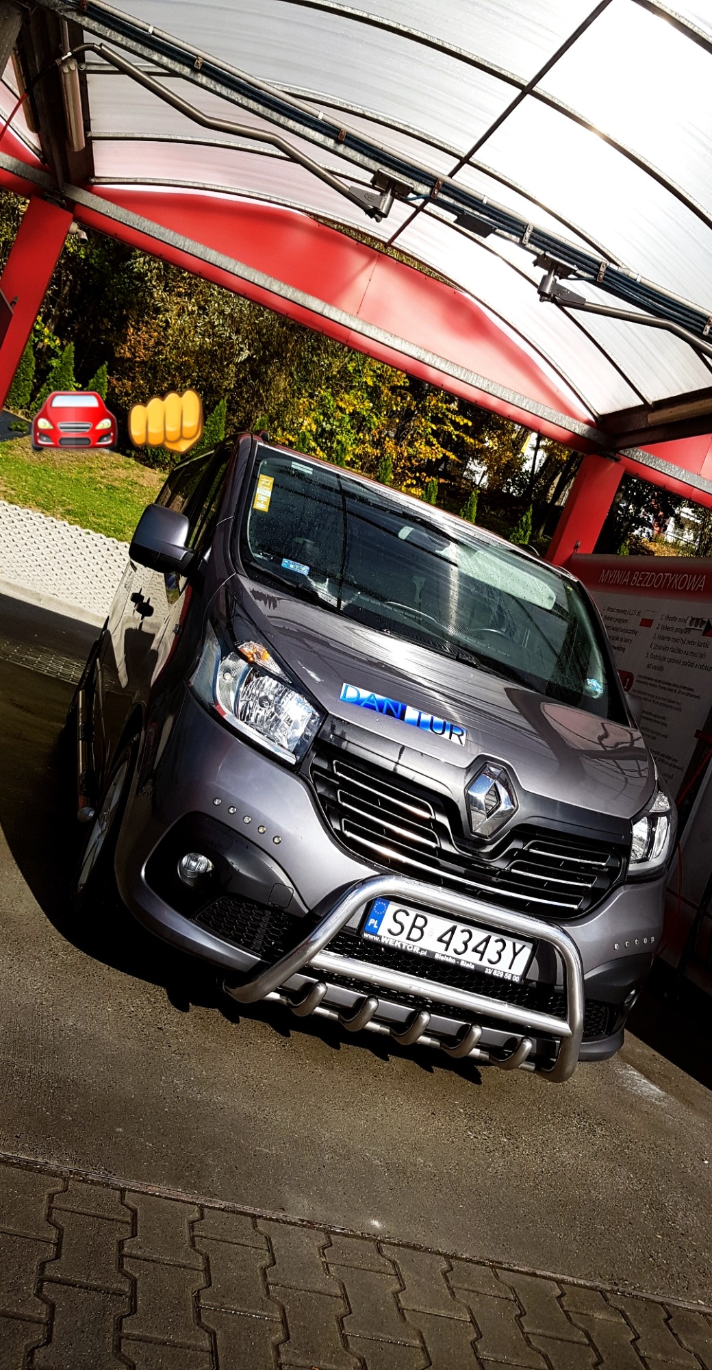 Szary van Renault z chromowanym orurowaniem przedniej części, zaparkowany w myjni bezdotykowej z tablicą rejestracyjną SB 4343Y.