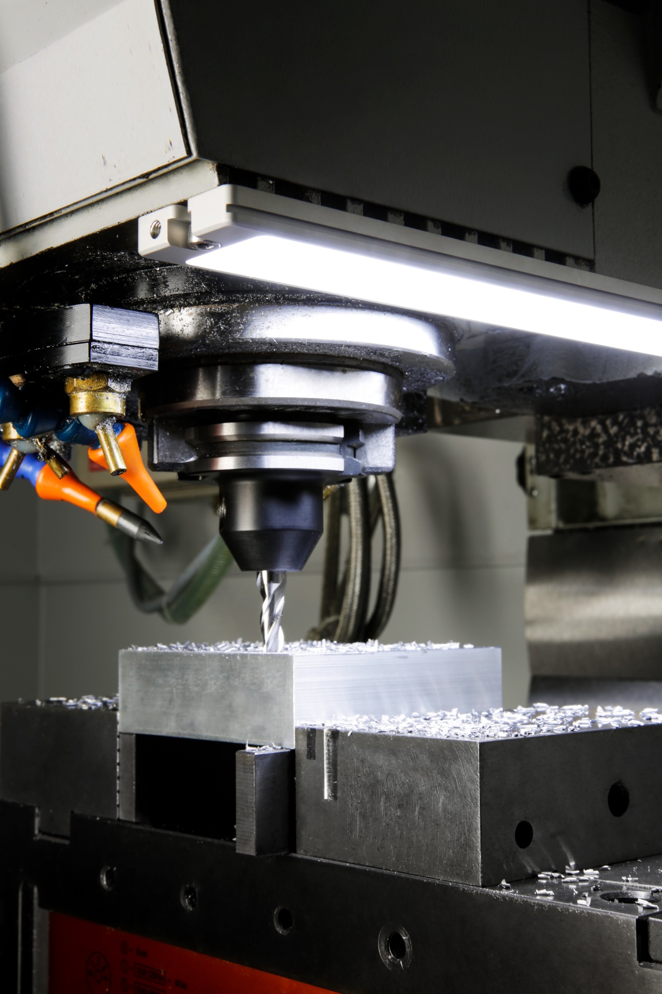 Obróbka metalu na frezarce CNC z chłodziwem, wióry na obrabianym elemencie, wewnętrzne, jasne doświetlenie procesu.