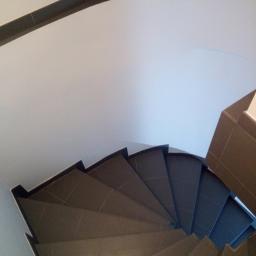 Prace wykończeniowe - Dominik Turczyn - Spiralne schody wyłożone brązowymi płytkami ceramicznymi, widok z góry, z ciemnobrązowym wykończeniem sufitu.