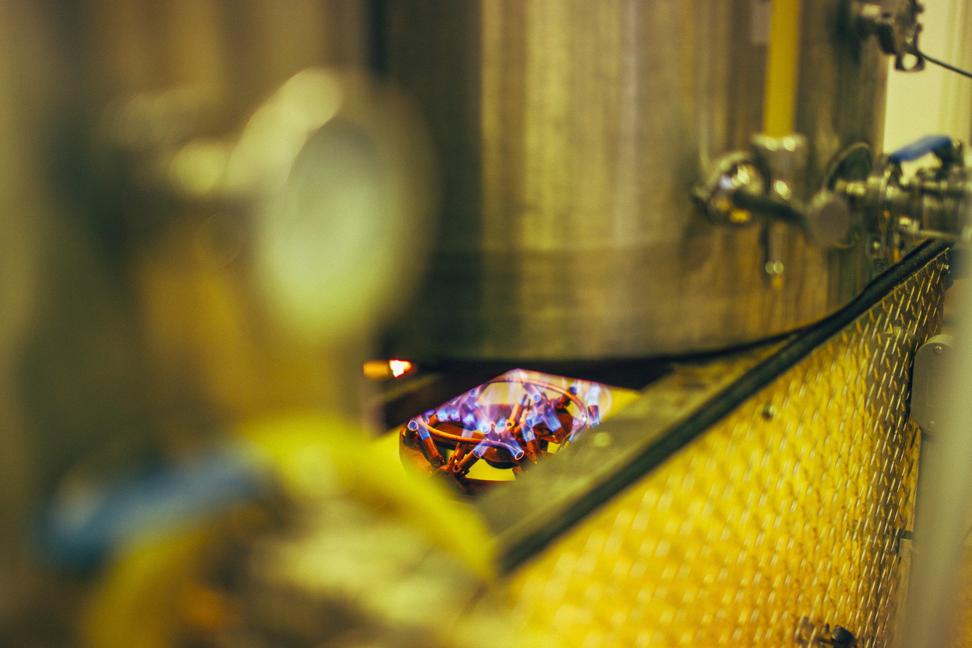 Detal fermentora z palnikiem gazowym, używanego w browarnictwie, widoczny przez otwór w osłonie.