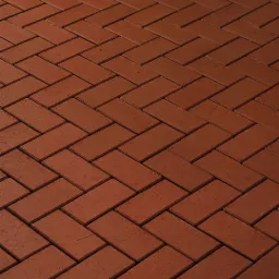 Czerwona kostka brukowa ułożona we wzór jodełki, z widoczną subtelną fakturą i ciepłym oświetleniem.