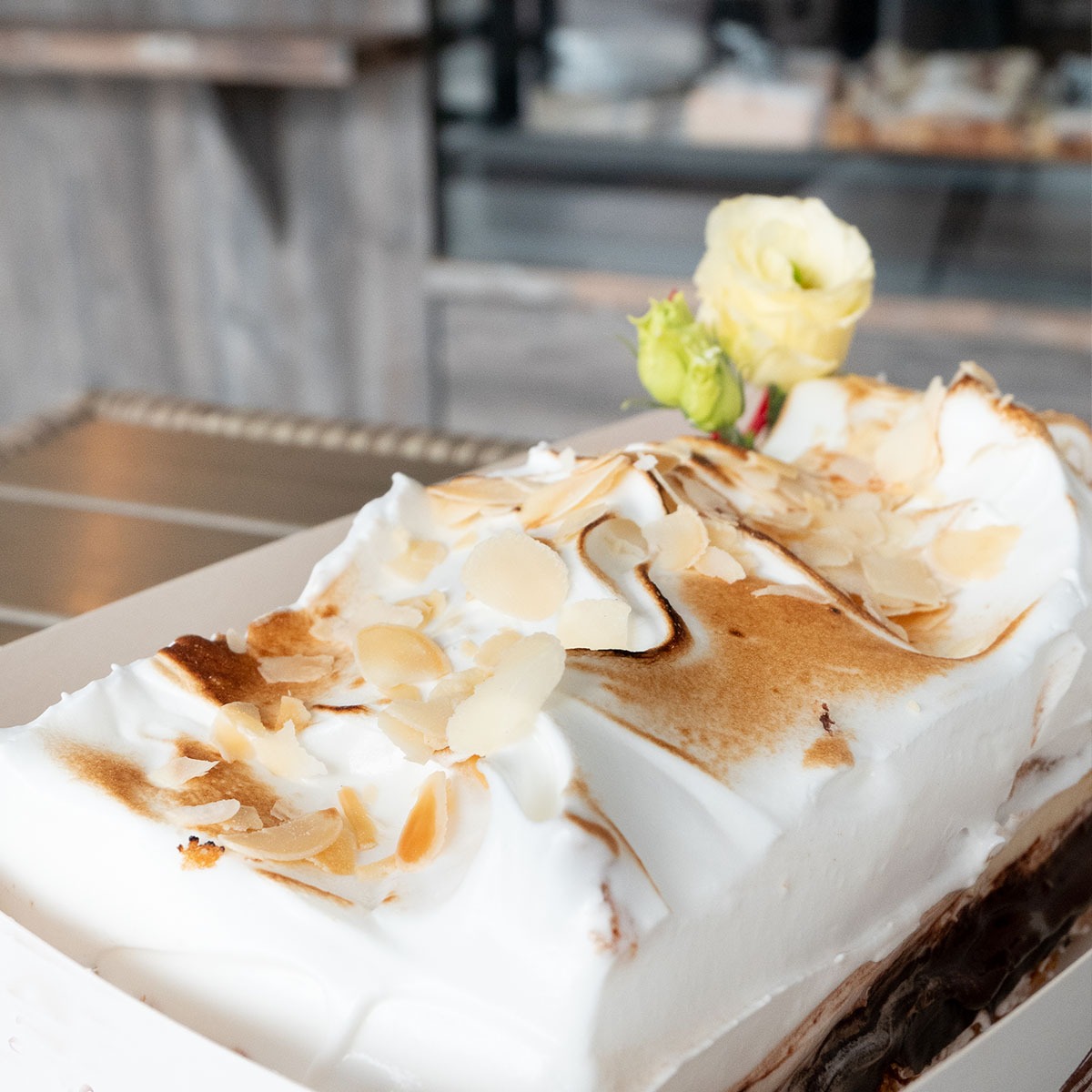 Królewski migdałowiec z kruchego spodu, czekolady, budyniu, prażonych migdałów z miodem i palonej bezy włoskiej, udekorowany kremową różą.