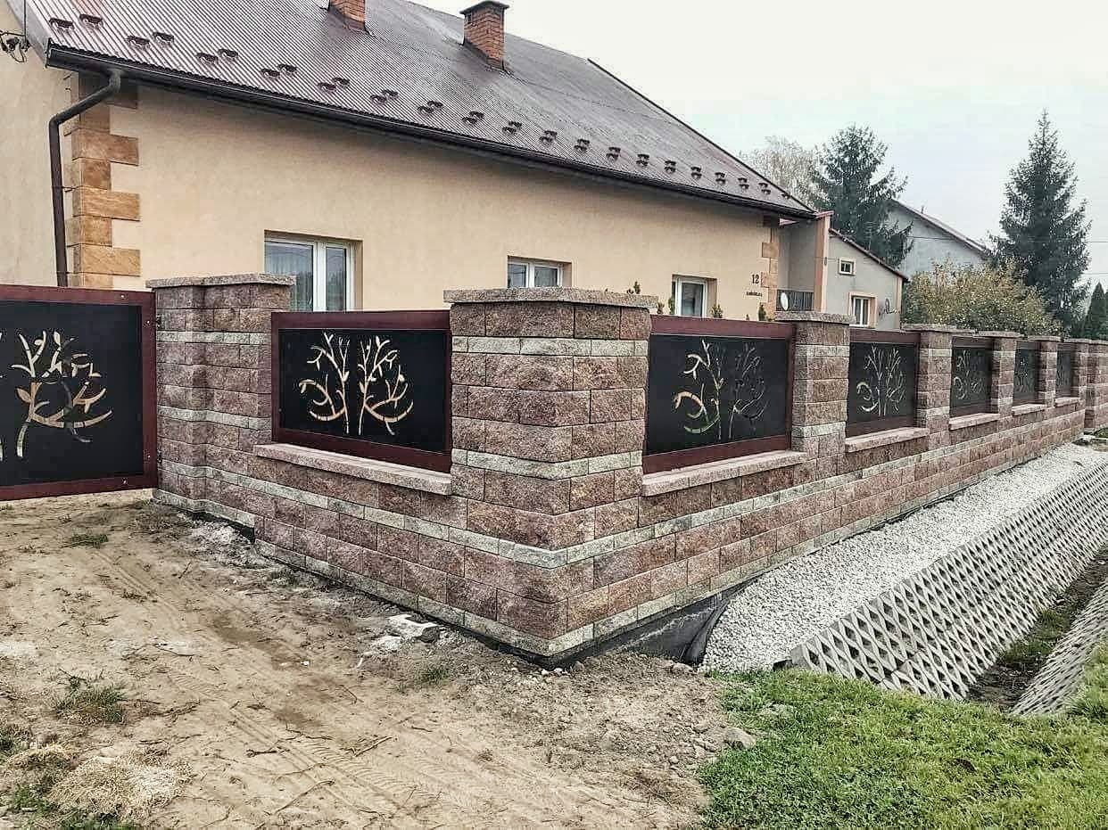 Nowoczesne ogrodzenie z cegły klinkierowej z czarnymi panelami dekoracyjnymi z motywem drzew, zabezpieczenie skarpy z ażurowych płyt betonowych.