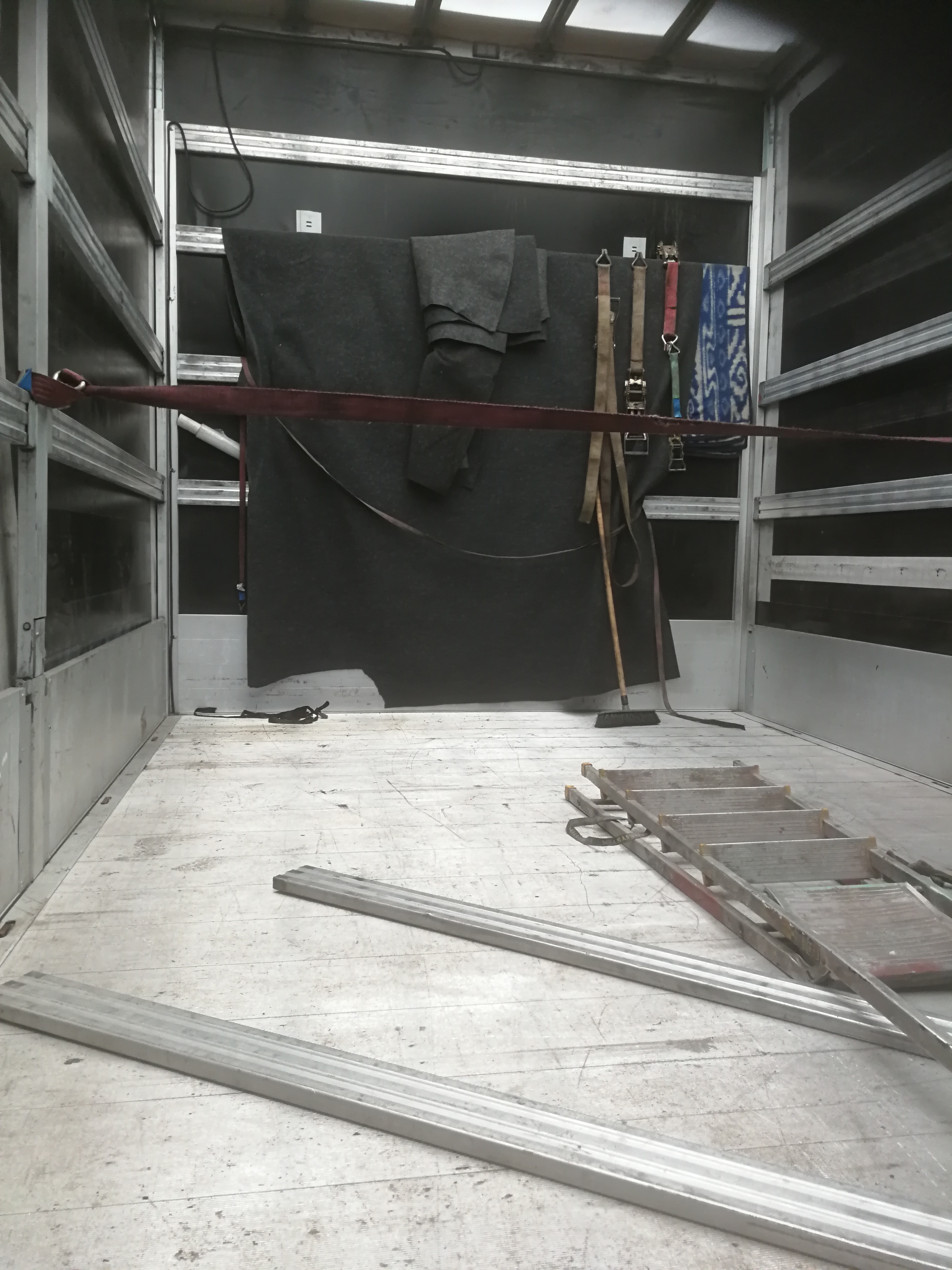 Wnętrze paki transportowej z zabezpieczeniami, kocami, pasami i drabiną, przygotowane do załadunku.