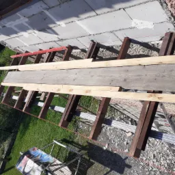 Przygotowanie rusztowania pod elewację w Stryszowie, widoczne drewniane belki i poziomica na tle surowych bloczków.