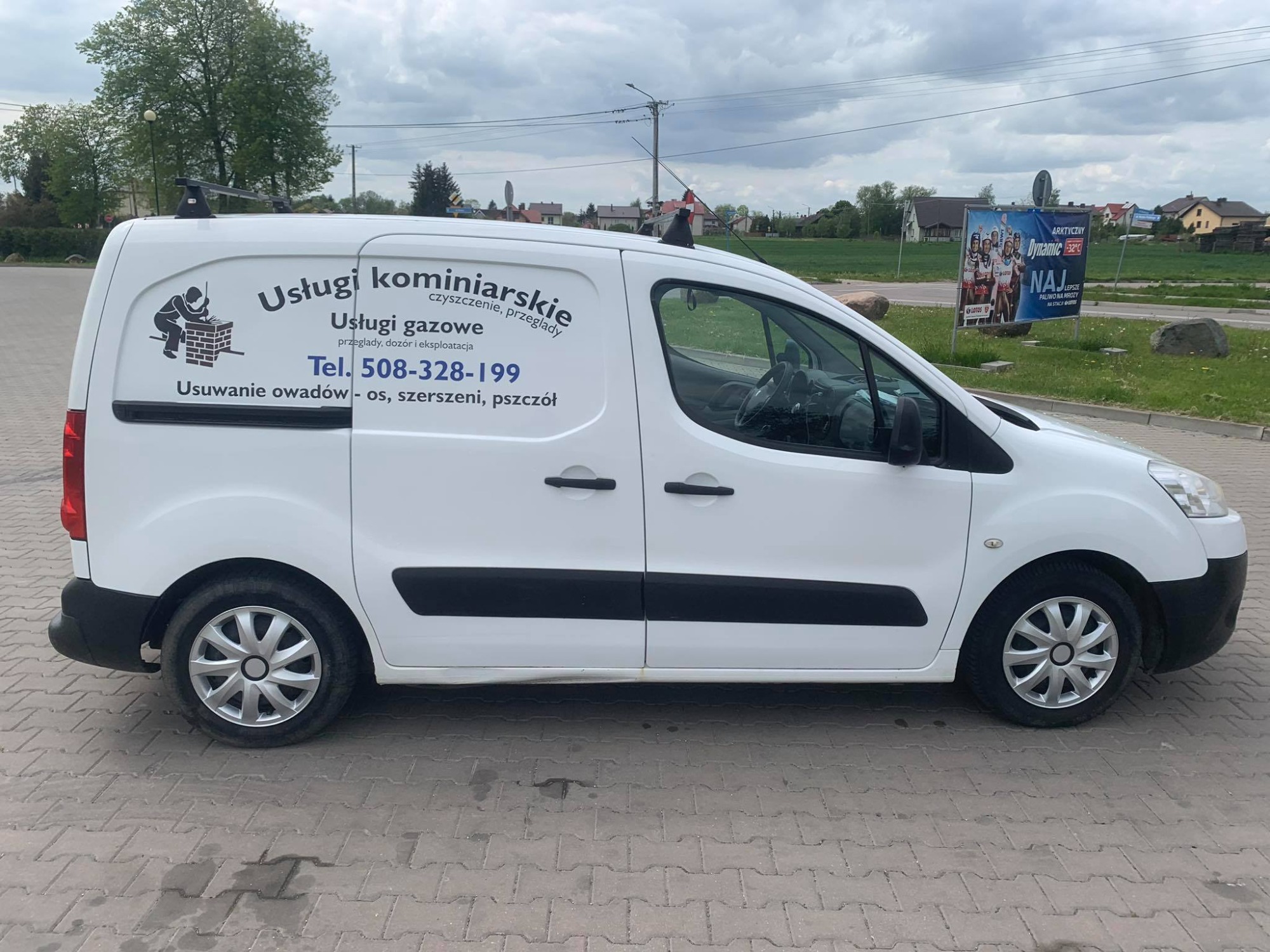 Biały samochód dostawczy z napisem 'Usługi kominiarskie, czyszczenie, przeglądy', 'Usługi gazowe, przeglądy, dozór i eksploatacja', 'Usuwanie owadów - os, szerszeni, pszczół' oraz numerem telefonu,...