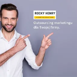 Uśmiechnięty mężczyzna w białej koszuli wskazuje palcami na tekst 'Outsourcing marketingu dla Twojej firmy' i logo 'Rocky Henry Marketing Solutions' na szarym tle.
