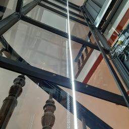 dźwig hydrauliczny w przeszklonej konstrukcji samonośnej zamontowany na klatce schodowej zabytkowego budynku