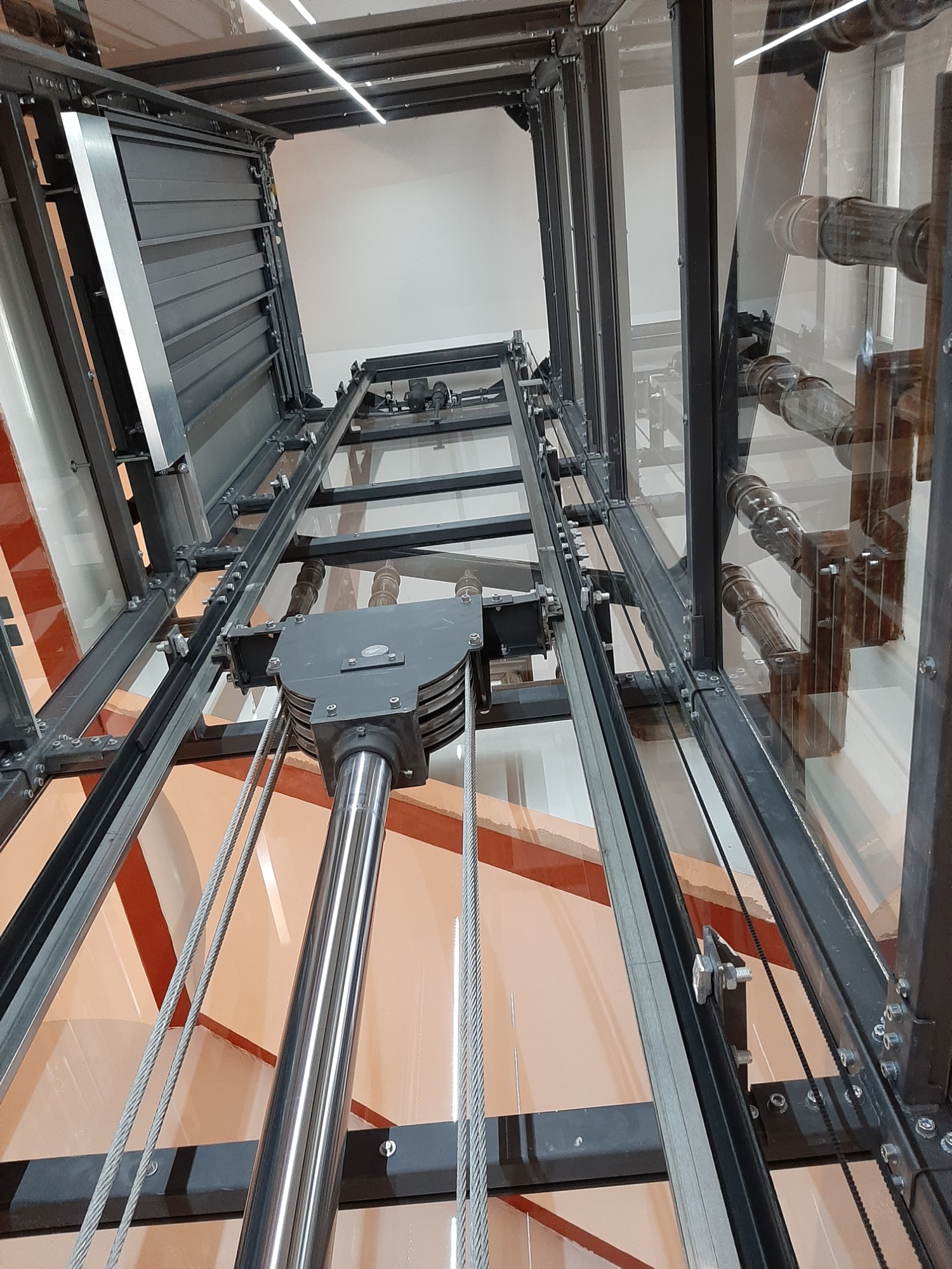 dźwig hydrauliczny w przeszklonej konstrukcji samonośnej zamontowany na klatce schodowej zabytkowego budynku