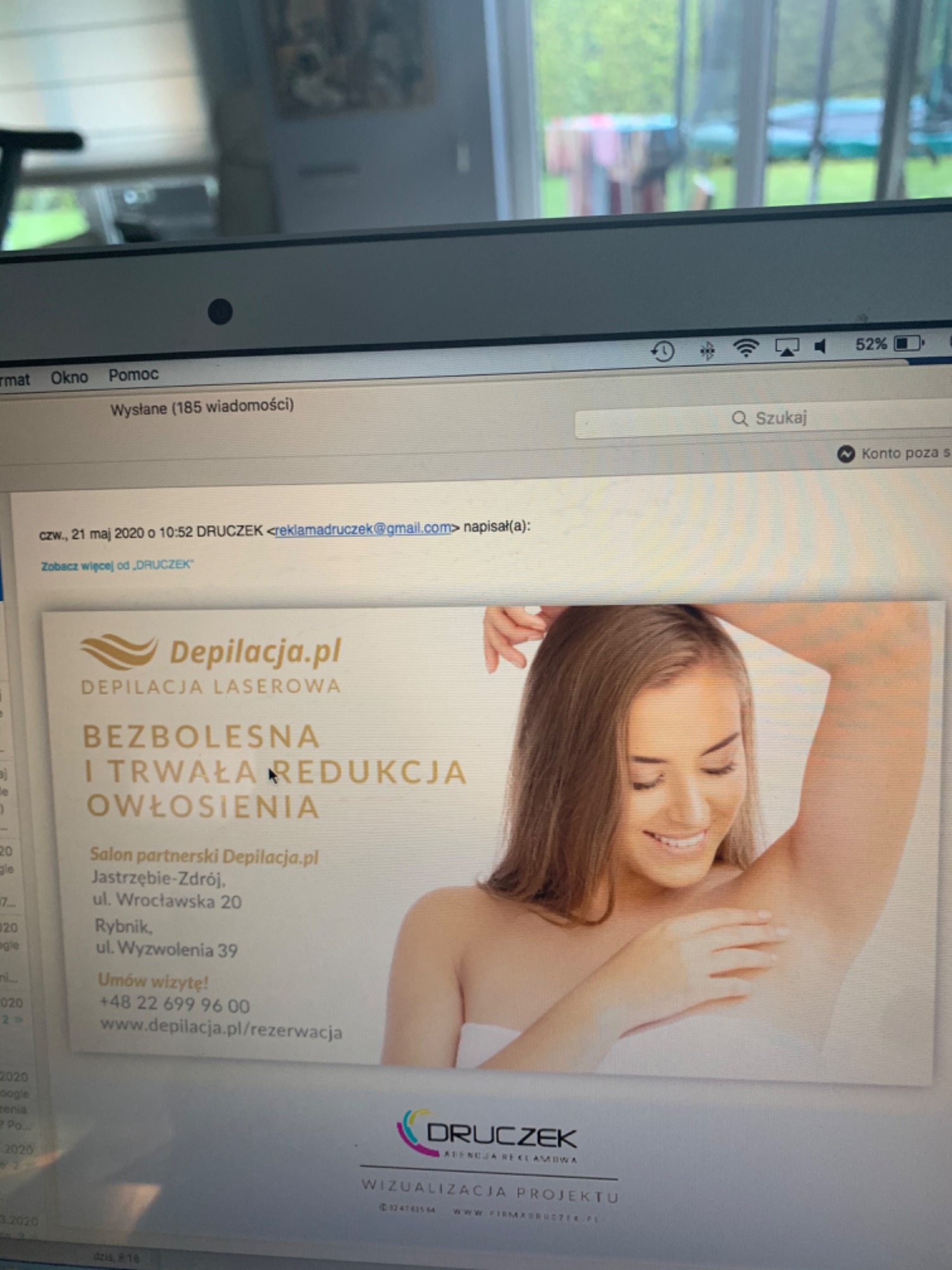 Zdjęcie ekranu laptopa z otwartą wiadomością e-mail zawierającą reklamę depilacji laserowej z uśmiechniętą kobietą prezentującą gładką skórę pod pachami.