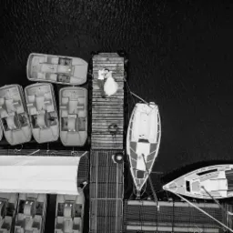 Zdjęcie z lotu ptaka: para młoda leżąca na drewnianym molo otoczonym łódkami i rowerami wodnymi na ciemnej wodzie.