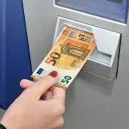 Wkładanie banknotu 50 euro do bankomatu; widoczne dłonie z czerwonym manicure.