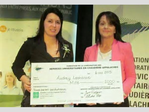 Dwie kobiety prezentują duży czek z napisem 'Audrey Lachance Mille' i kwotą 1000, na tle plakatu z logo organizacji.