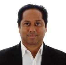 Portret uśmiechniętego mężczyzny w białej koszuli i czarnej marynarce na białym tle.