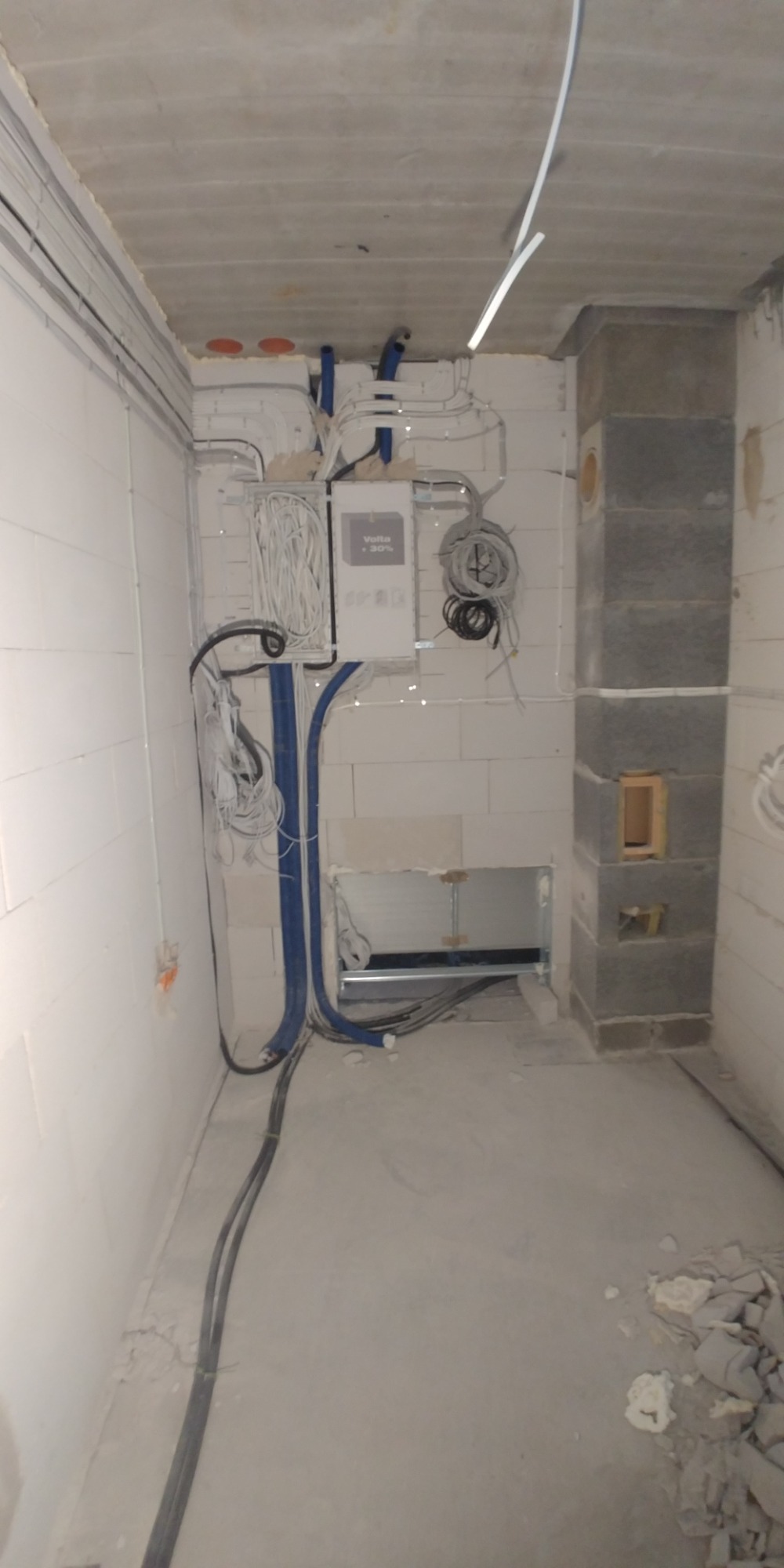 Wewnętrzne okablowanie elektryczne w surowym stanie, widoczne kable w peszlach, skrzynka elektryczna Volta +30% i instalacja podtynkowy kominek w trakcie budowy.