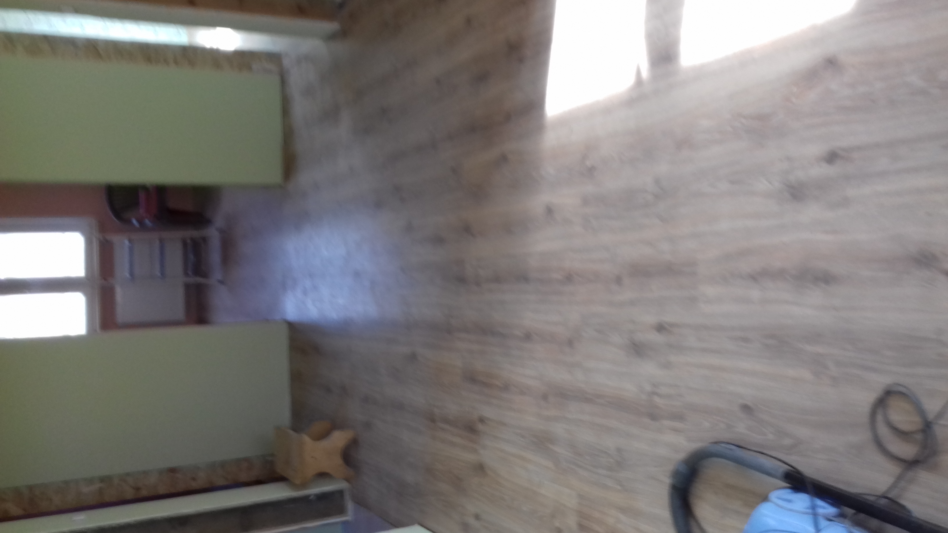 Układanie paneli podłogowych w pomieszczeniu, widoczny fragment podłogi z paneli, częściowo zamontowane szafki i odkurzacz.