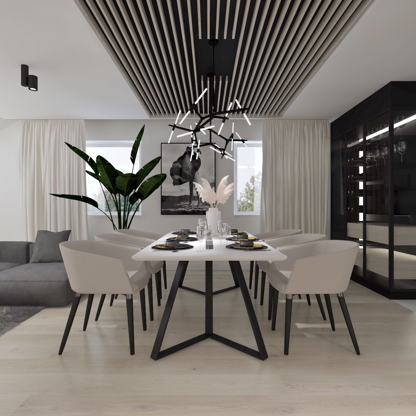 Nowoczesna jadalnia z białym stołem na czarnej, geometrycznej podstawie, beżowymi krzesłami, rośliną doniczkową i oryginalnym oświetleniem sufitowym w czarno-białej kolorystyce.