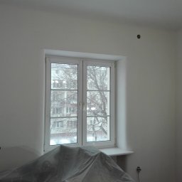 PRZEROBOTA Kamil Przesław - Przygotowanie do prac wykończeniowych: Pokój z oknem zabezpieczony folią malarską, ściany przygotowane do gładzi, widoczne puszki elektryczne.